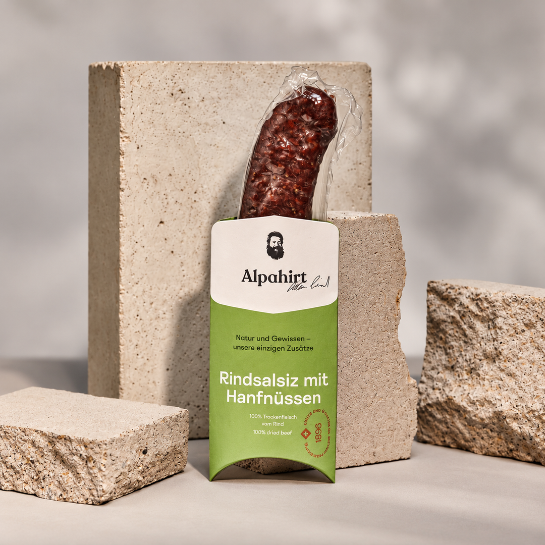 Alpahirt Rindsalsiz mit Hanfnüssen, 120 g, grüne Verpackung vor Steinblöcken